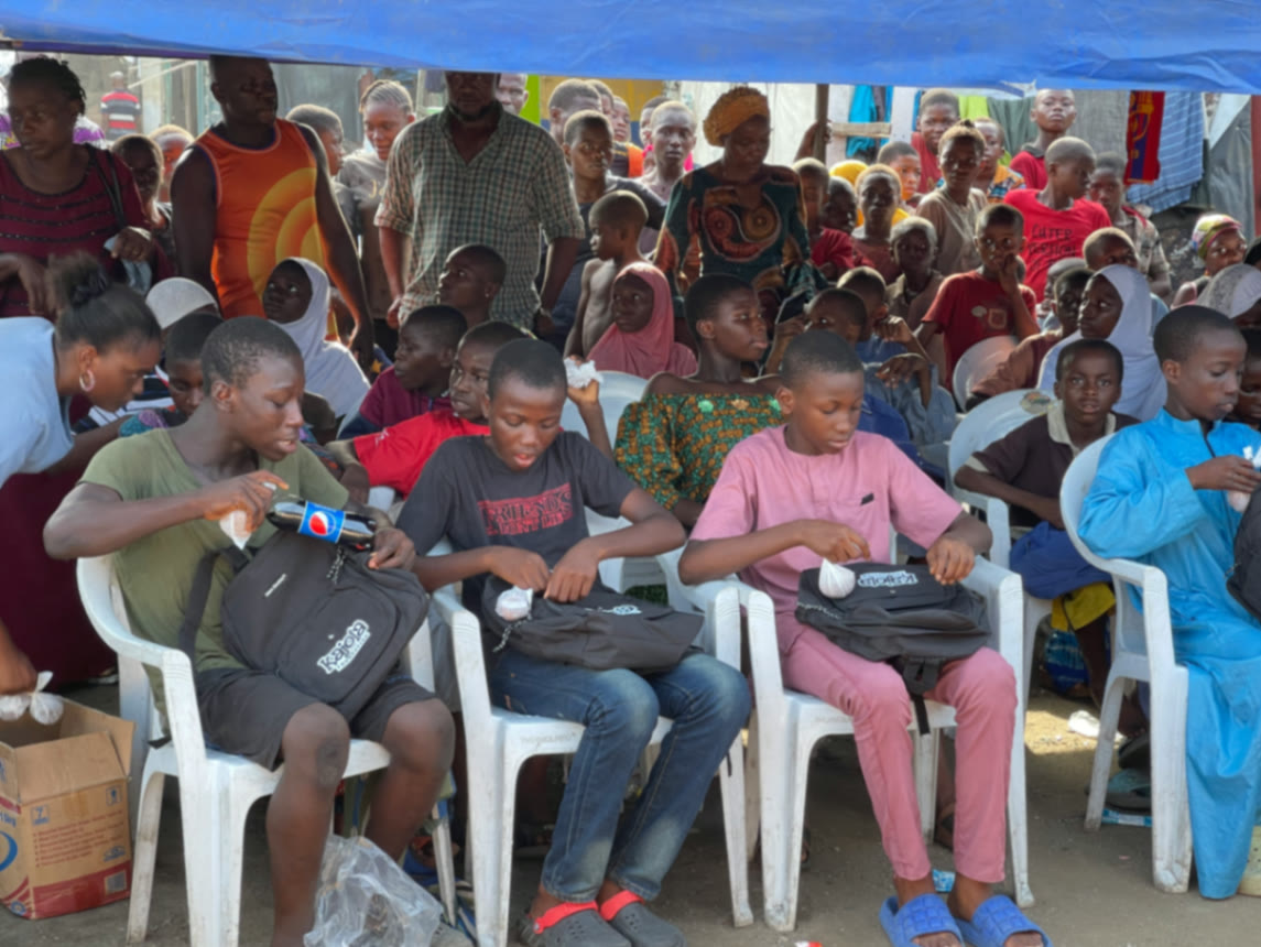 Children opening Kajola Foundation backpacks at a community outreach