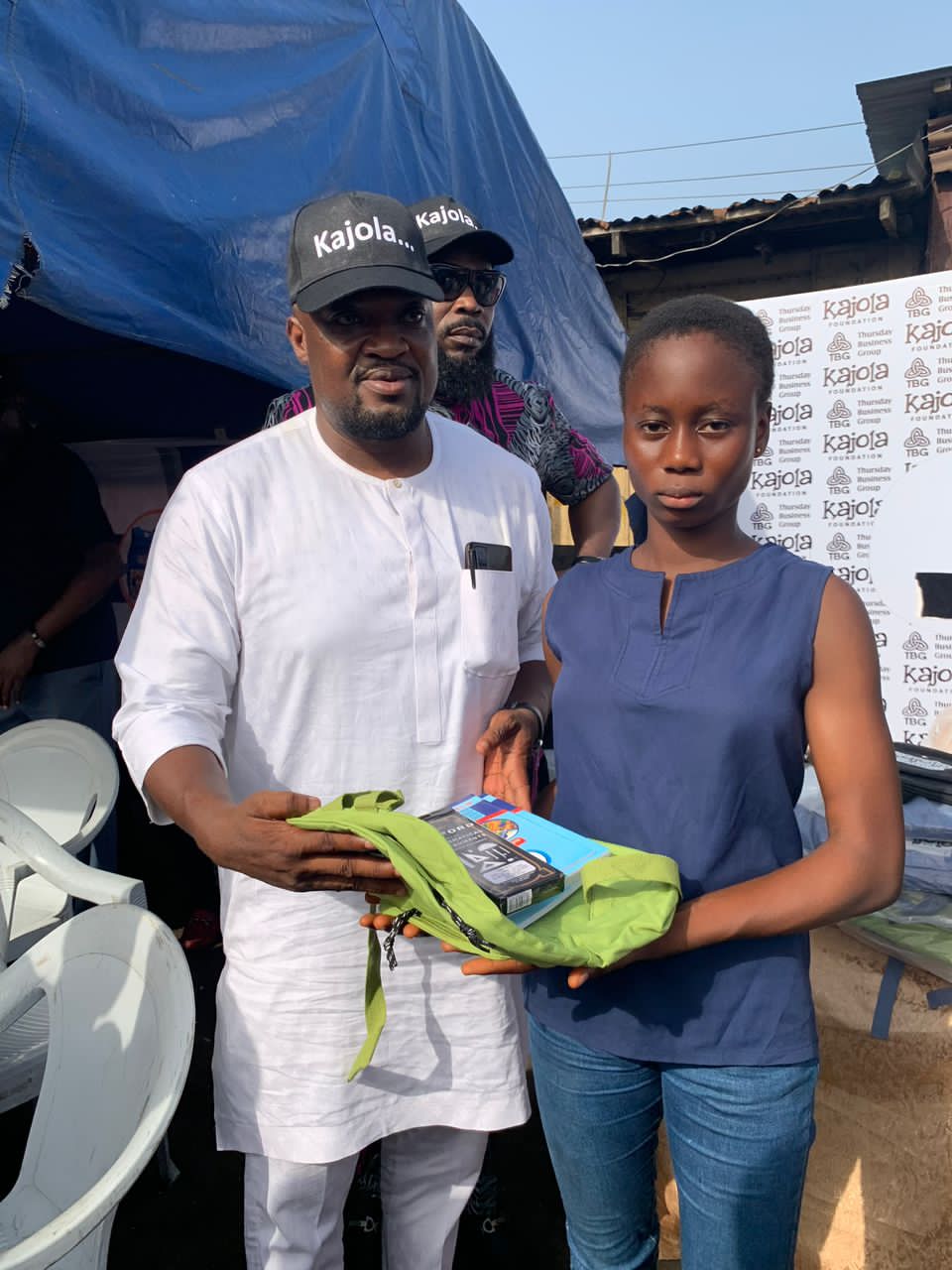 TBG member presenting a school bag and books to a student