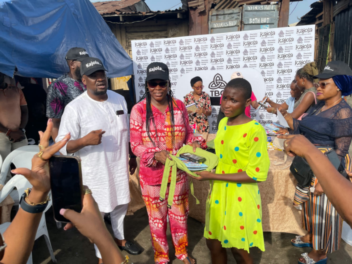 Kajola Foundation volunteers presenting a school bag to a girl at a street outreach